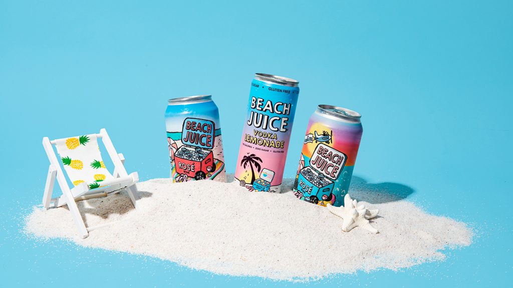 cans of beach juice in sand