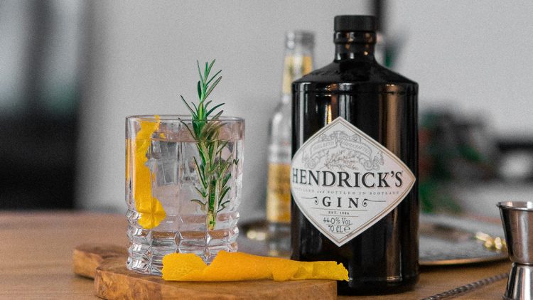 Hendricks gin on a table next to a cocktail