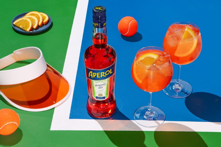 An aperol spritz on a tennis court.